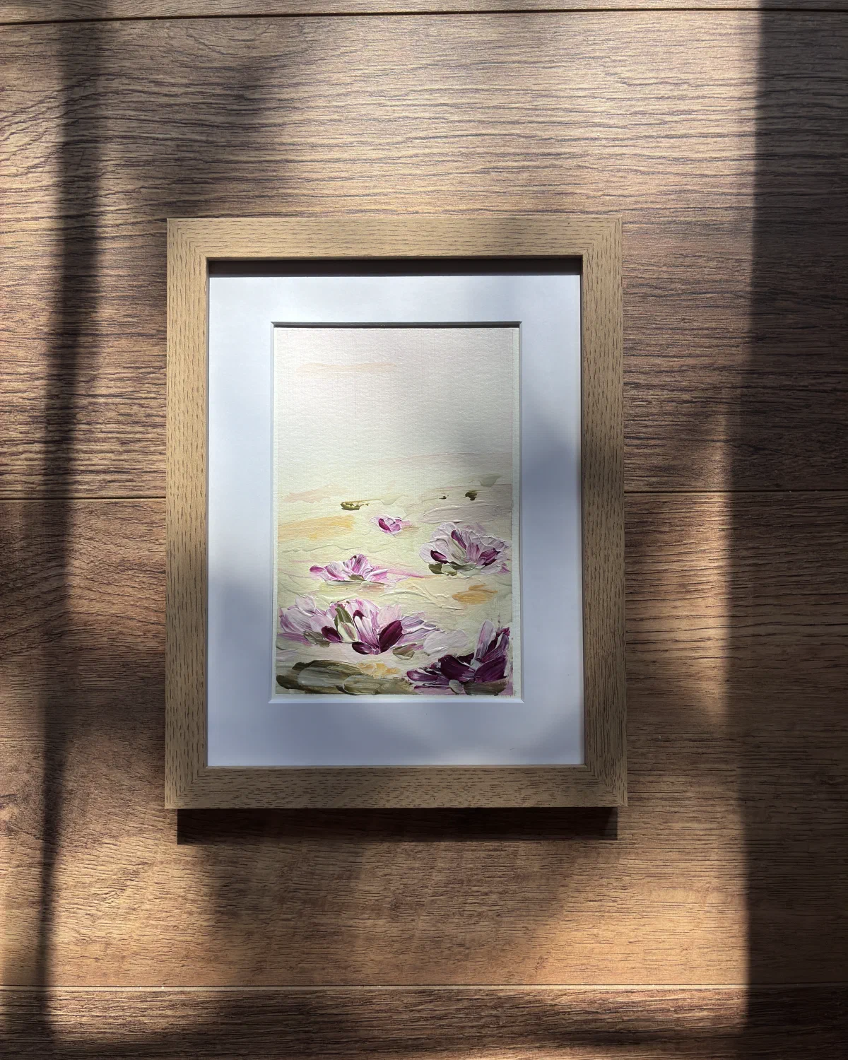 Deep Bloom in a light oak frame, hanging on a wall in afternoon sunlight